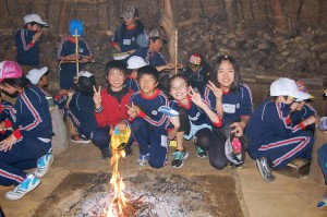 おこした火を竪穴住居の中の囲炉裏へ